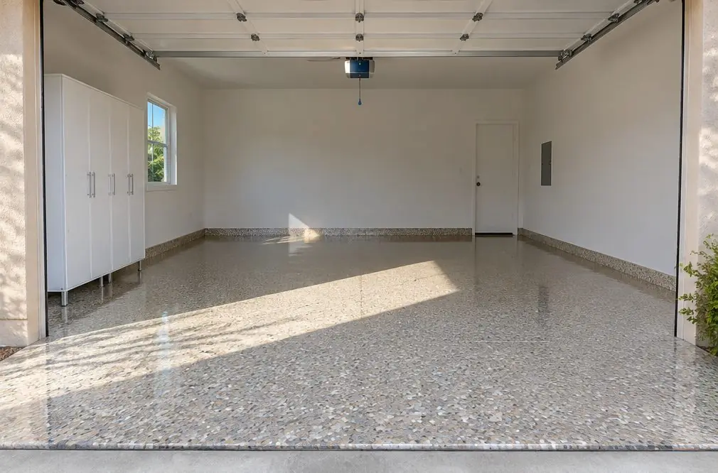 Illustration: a wide three-car garage floor in a bright polyaspartic flake system with a glossy clear coat and the door open to daylight